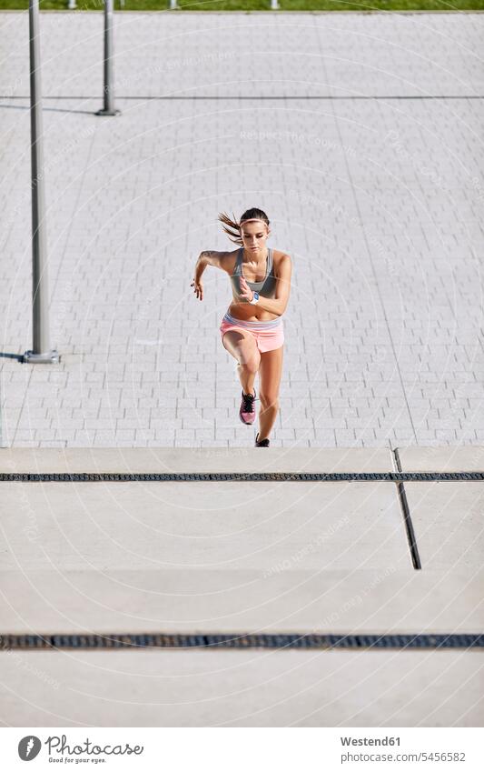 Fit young woman running on stairs exercising exercise training practising fit females women stairway Adults grown-ups grownups adult people persons human being