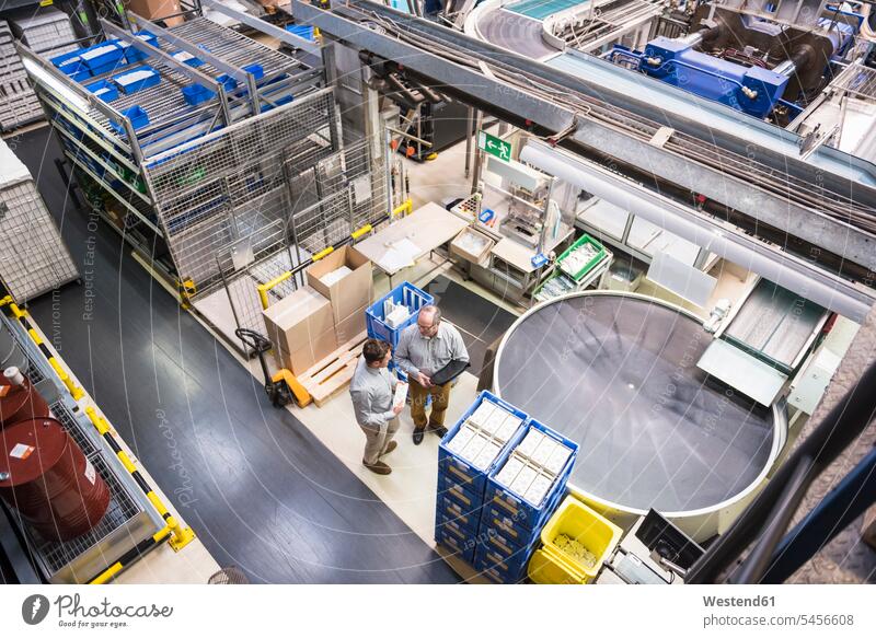 Top view of two men talking in factory shop floor speaking man males factories colleagues Adults grown-ups grownups adult people persons human being humans