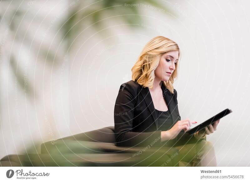 Businesswoman sitting on couch using tablet digitizer Tablet Computer Tablet PC Tablet Computers iPad Digital Tablet digital tablets businesswoman businesswomen