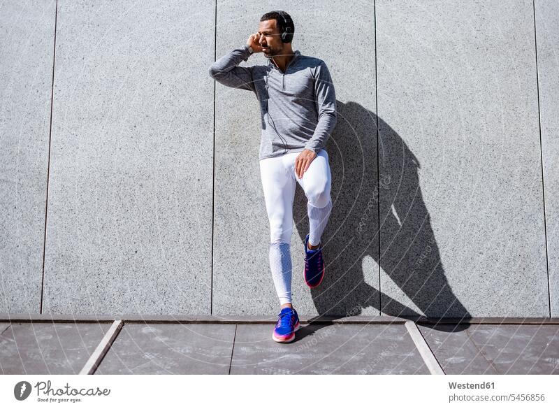 Man having a break from exercising wearing headphones exercise training practising headset man men males Adults grown-ups grownups adult people persons