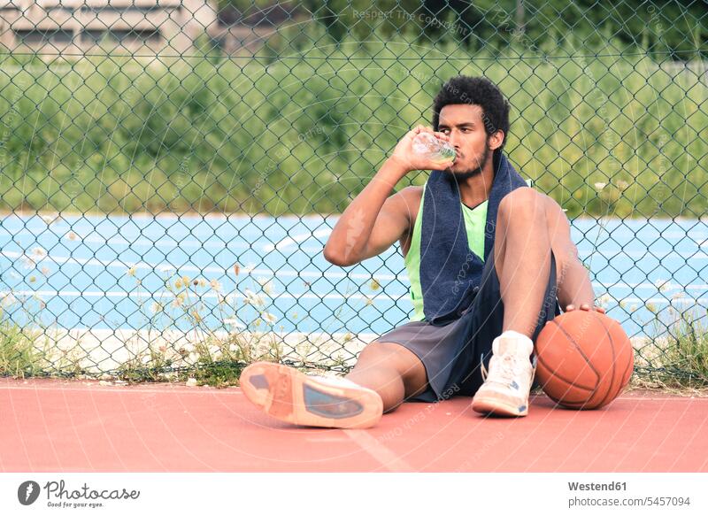 Young basketball player drinking from water bottle leisure free time leisure time sitting Seated water bottles bottled water basketballs break