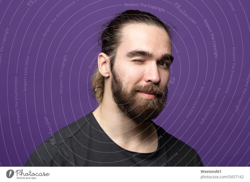 Portrait of bearded young man winking against purple background human human being human beings humans person persons caucasian appearance caucasian ethnicity