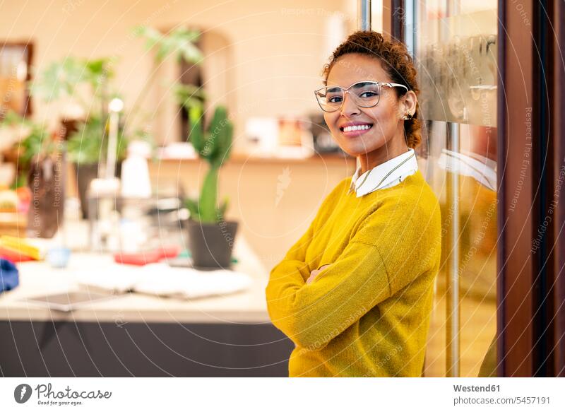 Young woman standing in door of a fashion store, smiling young women young woman fashion shop boutique fashion boutique smile glasses specs Eye Glasses