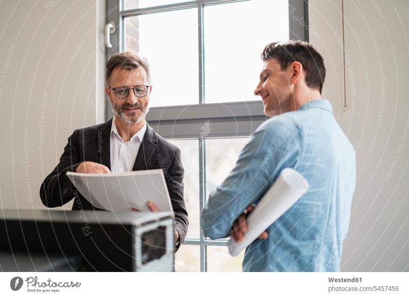 Two colleagues talking at the window in office speaking offices office room office rooms windows workplace work place place of work consultancy consulting