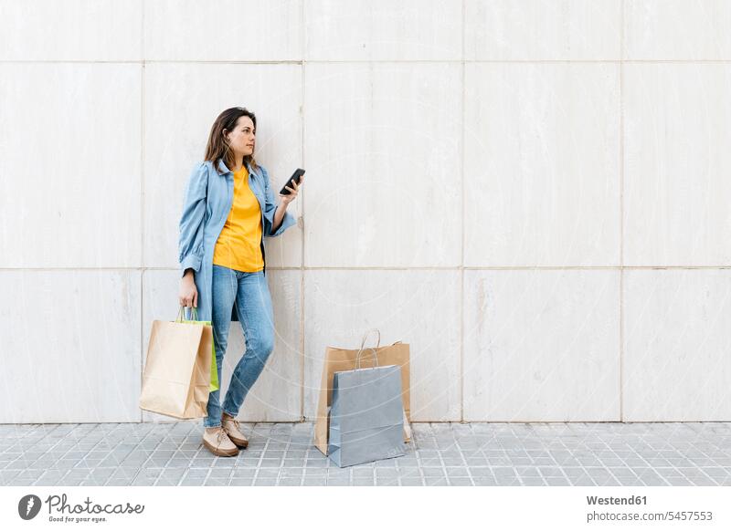Young brunette woman using smartphone after shopping human human being human beings humans person persons caucasian appearance caucasian ethnicity european 1