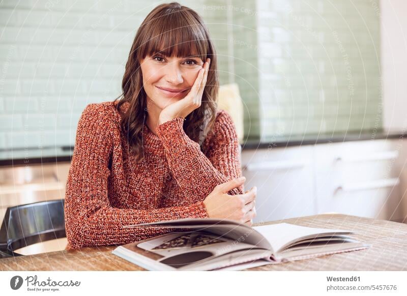 Mature woman sitting in kitchen, reading book smiling smile brown hair brown haired brown-haired brunette caucasian caucasian ethnicity caucasian appearance