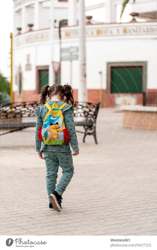 Rear view of girl walking with backpack and mask on square - a Royalty ...