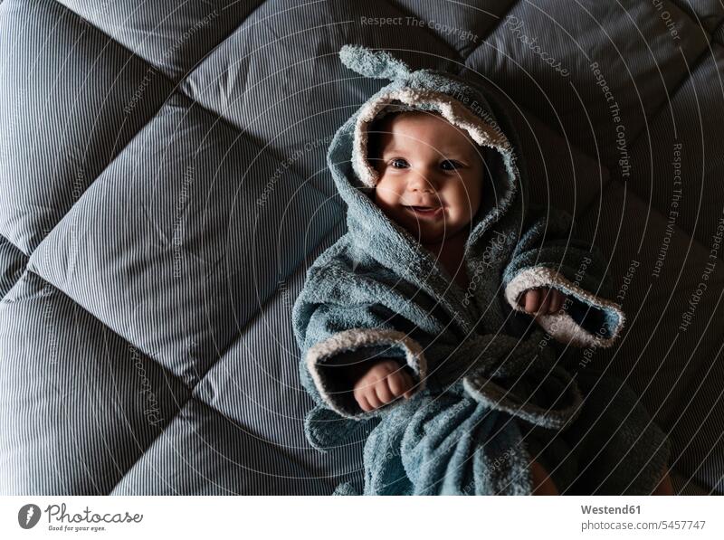 Portrait of happy baby girl lying on bed wrapped with shark shaped towel after bath sharks towels Bed - Furniture beds relax relaxing smile relaxation delight