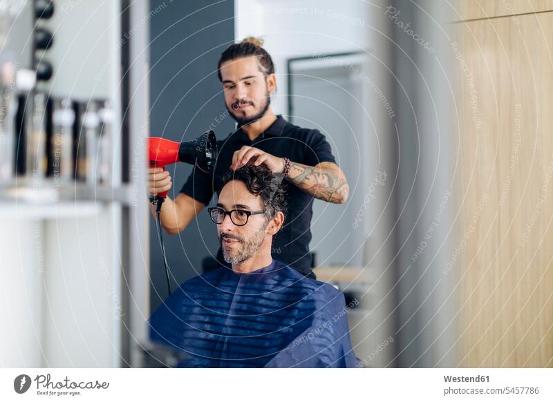 Hairdresser blow drying man s hair at salon a Royalty Free Stock Photo from Photocase