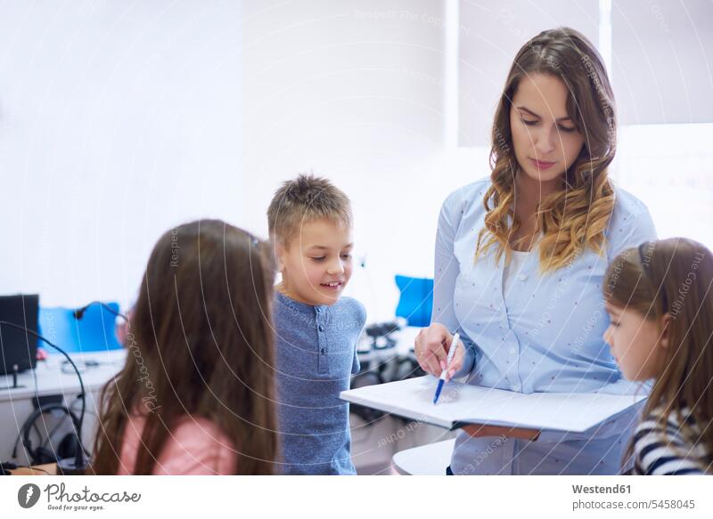 Teacher with pupils checking class register in class school schools teacher instructor teachers school class student class-book pedagogue pedagogues education