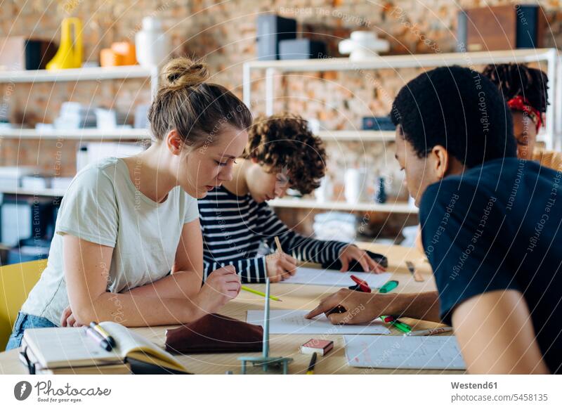 Young people sitting together at table and talking human human being human beings humans person persons adult grown-up grown-ups grownup grownups male males men