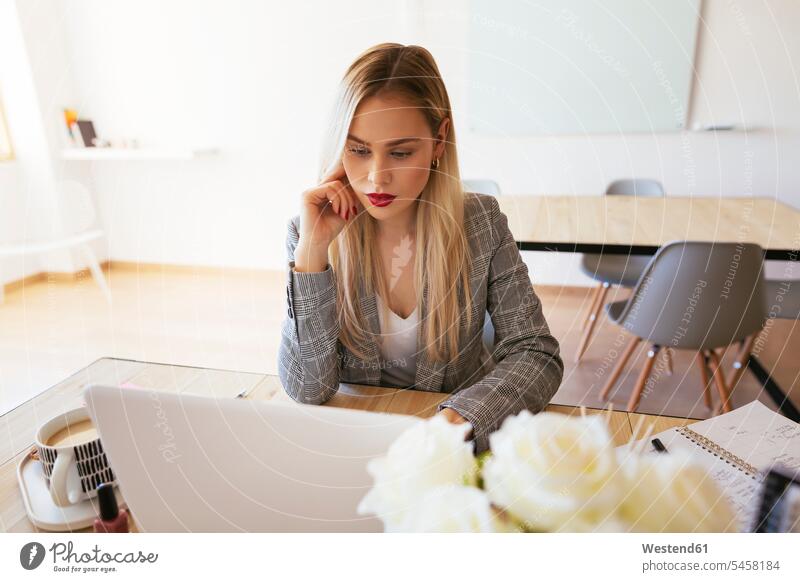 Young businesswoman working in office, using laptop businesswomen business woman business women Laptop Computers laptops notebook At Work sitting Seated blond