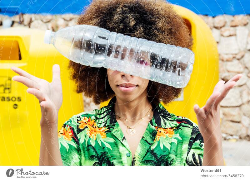 Young woman throwing empty plastic bottle in front of recycling bin material materials recources hold collect collected Yellow - Color trash waste location shot