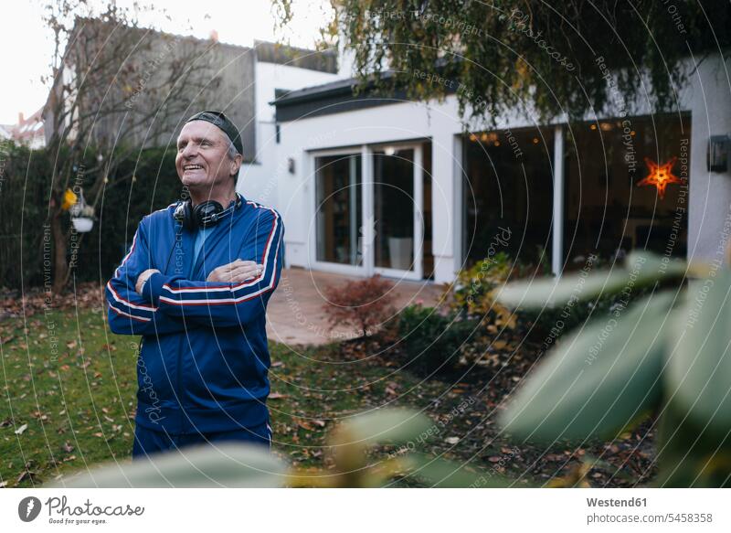 Happy sportive senior man in tracksuit standing in garden visored cap visor cap exhilaration Cheerfulness glad Joyous merry gleeful free time leisure time laugh