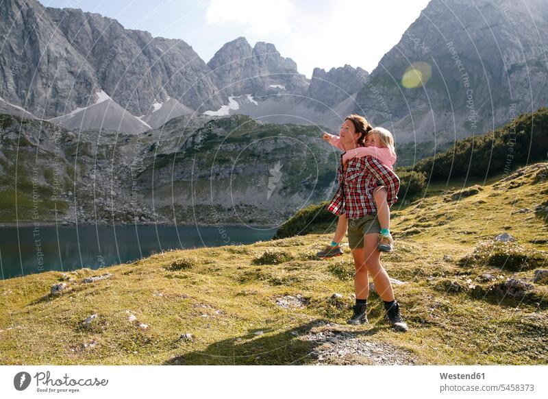 Austria, Tyrol, mother carrying daughter piggyback at lake Drachensee piggy-back pickaback Piggybacking Piggy Back lakes mommy mothers ma mummy mama daughters