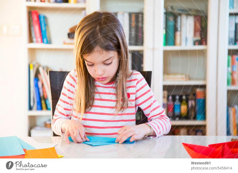 Girl tinkering with paper on table at home crafting doing handicrafts Table Tables girl females girls child children kid kids people persons human being humans