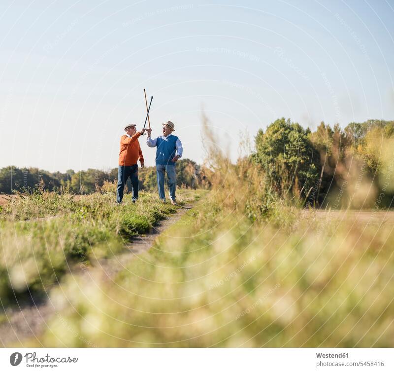 Two old friends fencing in the fields with their walking sticks Field Fields farmland rival rivals fighting fence Hiking Sticks Walking Cane playing Best Friend