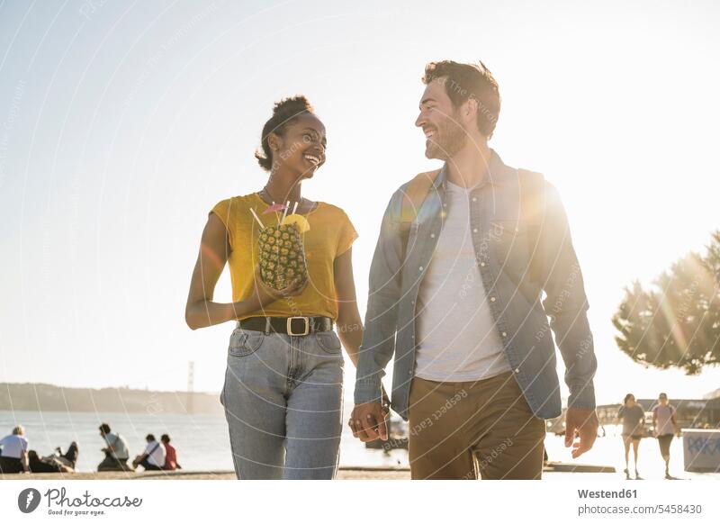 Happy young couple walking at the waterfront at sunset, Lisbon, Portugal touristic tourists smile in the evening Late Evening seasons summer time summertime