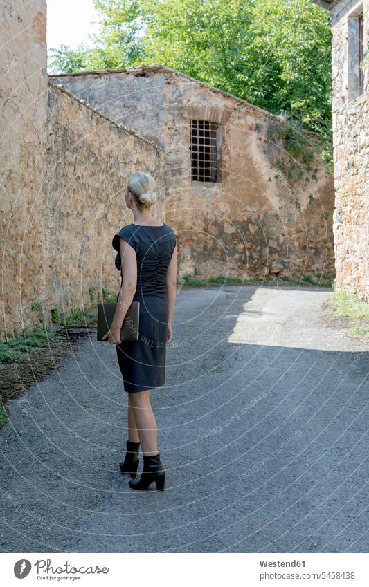 Italy, Tuscany, Monteriggioni, woman with laptop walking in the village Village Villages females women Laptop Computers laptops notebook going Adults grown-ups