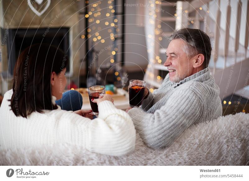 Happy mature couple with hot drinks in living room relaxed relaxation Hot Drink Hot Drinks twosomes partnership couples sitting Seated happiness happy
