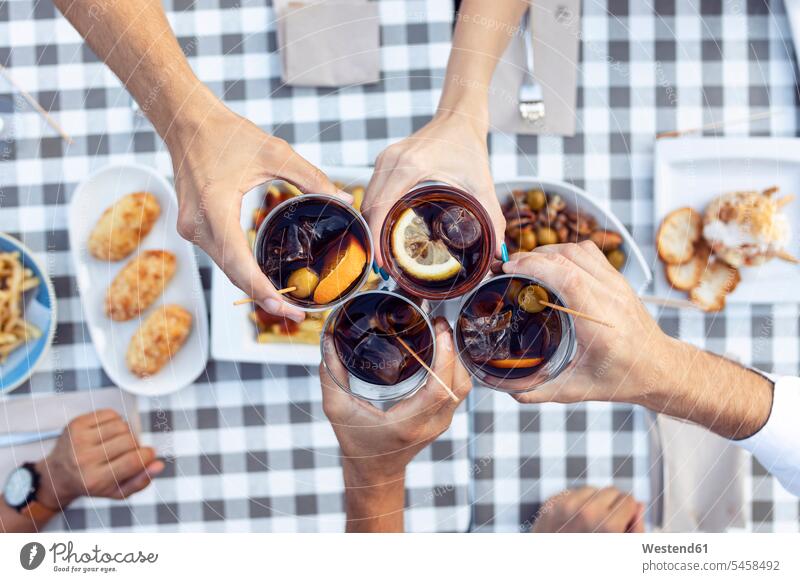 Hands of friends toasting vermouth at table in cafe color image colour image outdoors location shots outdoor shot outdoor shots day daylight shot daylight shots