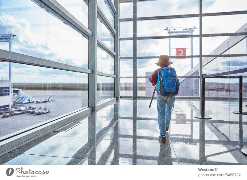 Boy with backpack at the airport running towards departure gate boy boys males rucksacks backpacks back-packs airports child children kid kids people persons