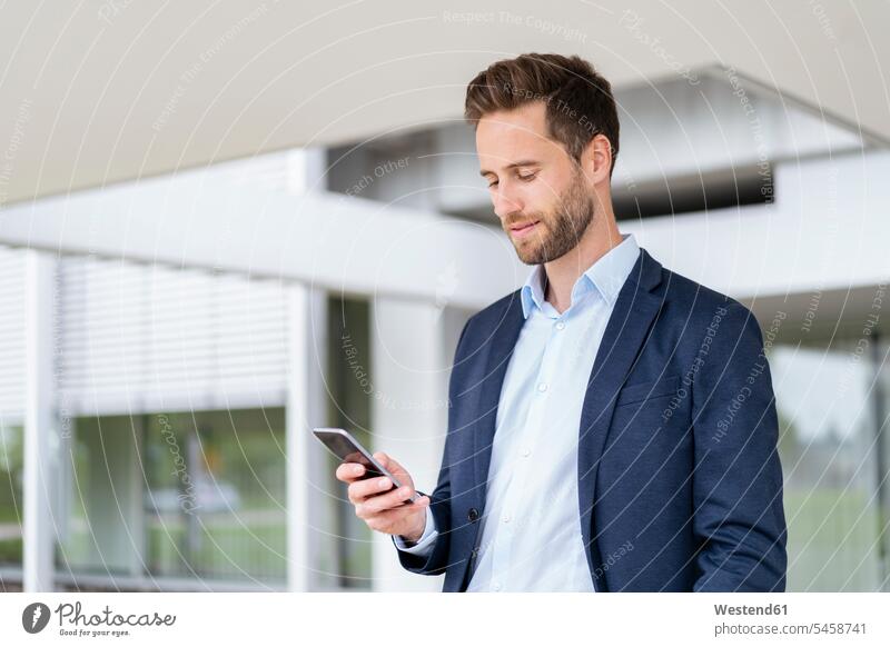 Businessman with cell phone standing outdoors human human being human beings humans person persons caucasian appearance caucasian ethnicity european 1