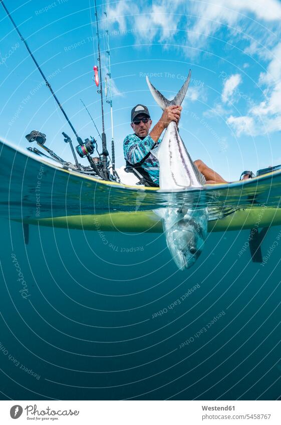 Split shot of man in a kayak catching a fish touristic tourists animals creature creatures Fishes angling rod fishing pole fishing poles Fishing Rods