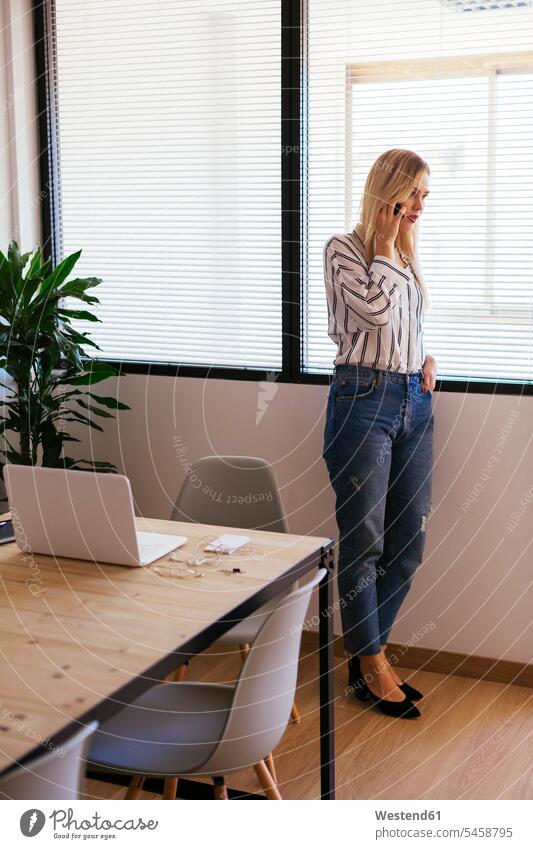 Businesswoman standing at the window, talking on the phone windows call telephoning On The Telephone calling businesswoman businesswomen business woman