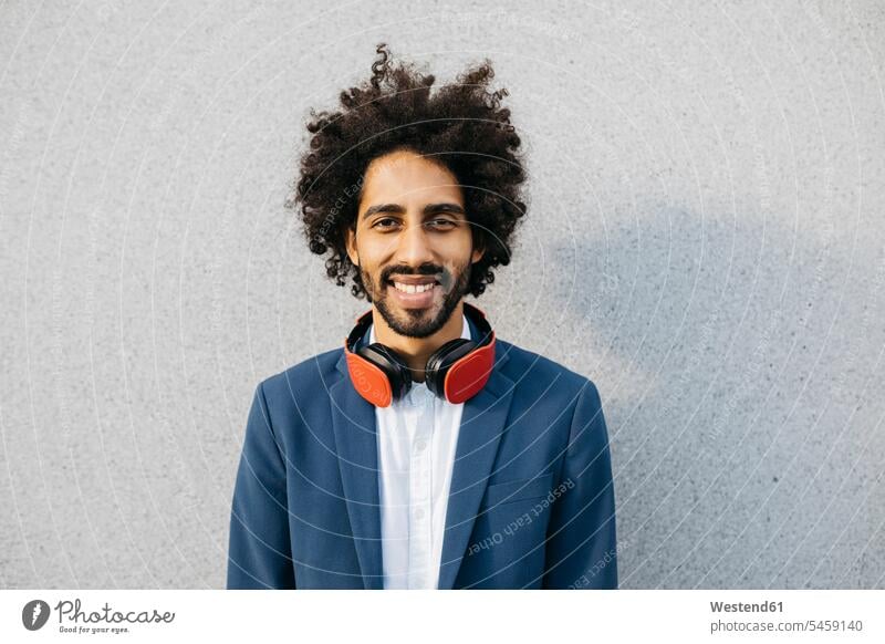 Portrait of smiling young businessman with headphones at a wall smile men males portrait portraits Businessman Business man Businessmen Business men headset