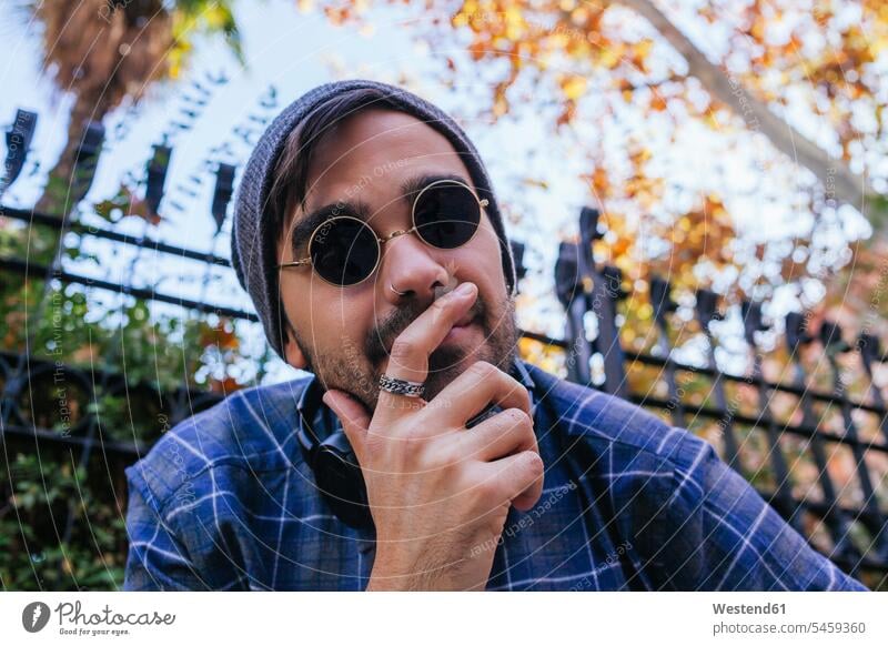 Young man with cool attitude wearing nose ring at public park color image colour image outdoors location shots outdoor shot outdoor shots day daylight shot