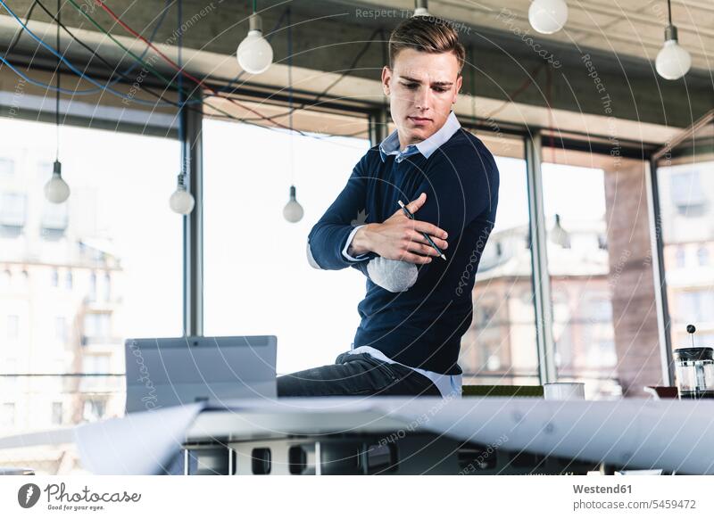 Male professional contemplating while looking at document on desk in office color image colour image Germany indoors indoor shot indoor shots interior