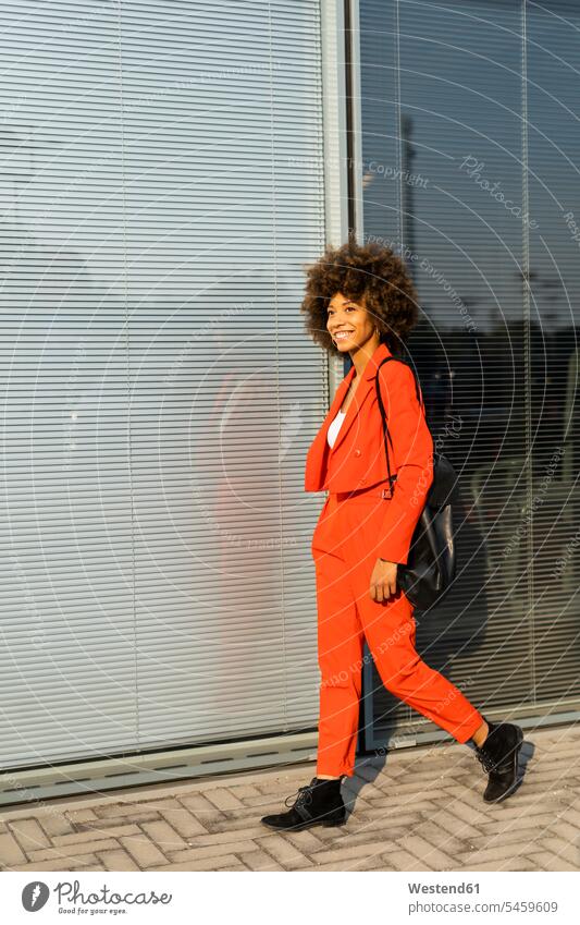 Smiling young woman with shoulder bag wearing fashionable red pantsuit human human being human beings humans person persons Mixed Race mixed race ethnicity