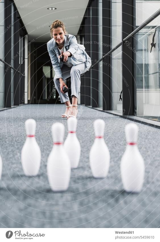 Smiling businessman bowling in office passageway Office Offices Bowling smiling smile businesswoman businesswomen business woman business women dexterity game