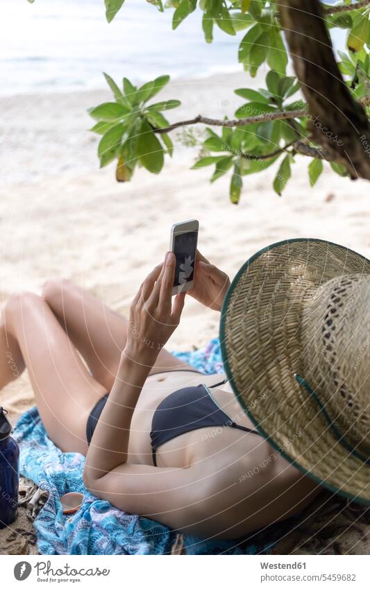 Young lying woman on the beach, using smartphone reading young women young woman beaches Smartphone iPhone Smartphones sea ocean vacation Holidays females