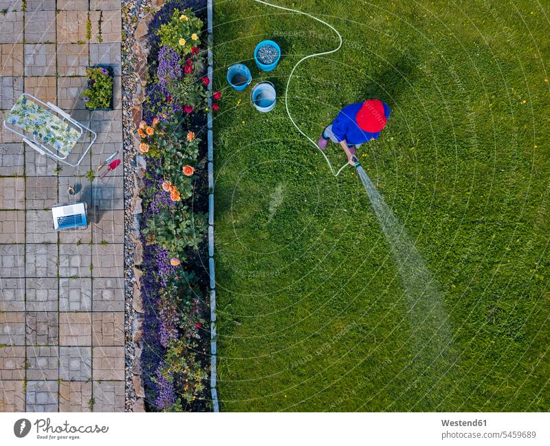 Aerial view of adult woman watering grass in backyard outdoors location shots outdoor shot outdoor shots day daylight shot daylight shots day shots daytime