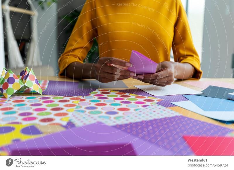 Origami artist sitting in studio folding colorful paper human human being human beings humans person persons African black black ethnicity coloured