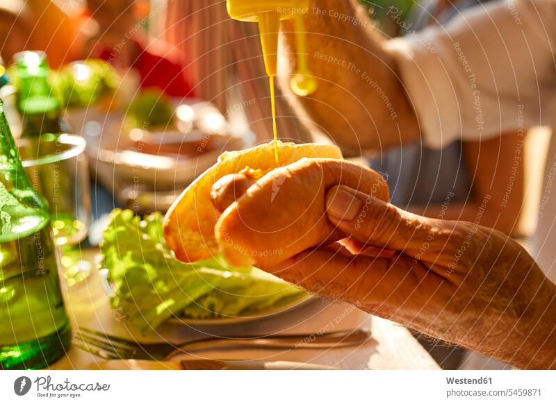 Senior man preparing a hot dog on a garden party Celebration Celebrations Celebration Event Ceremonies Festivity Ceremony Festivities preparation prepare