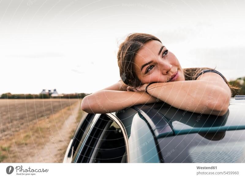 Smiling young woman looking out of sunroof of a car automobile Auto cars motorcars Automobiles females women view seeing viewing smiling smile motor vehicle