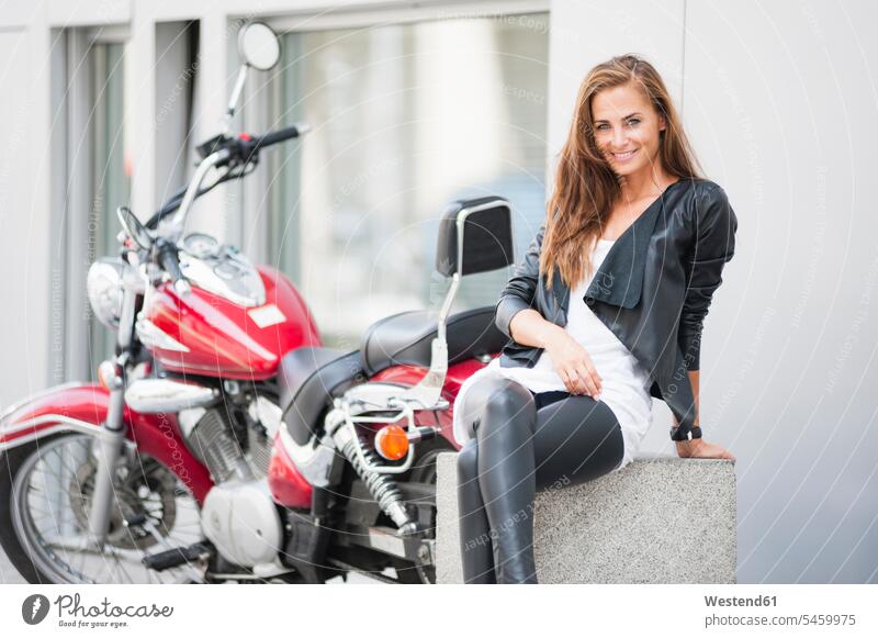 Portrait of smiling woman sitting in front of motorbike in the city motor vehicles road vehicle road vehicles Motor Cycle motorbikes motorcycle motorcycles