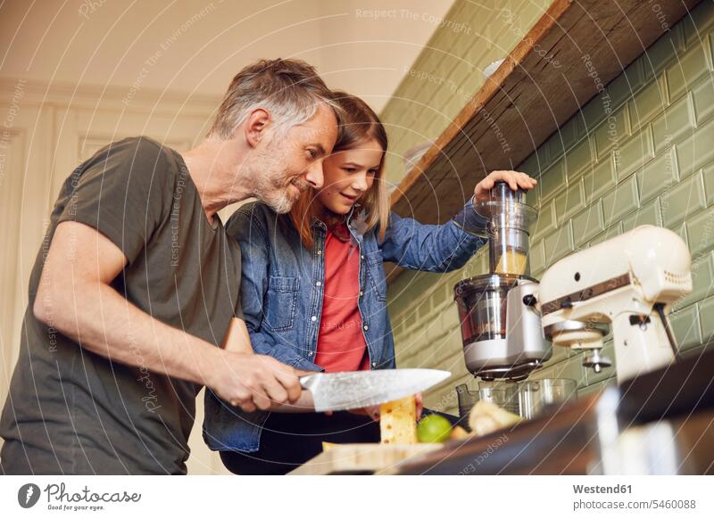 Father and daughter in kitchen preparing a smoothie devices blender Electric Mixer food mixer mixers smile delight enjoyment Pleasant pleasure happy