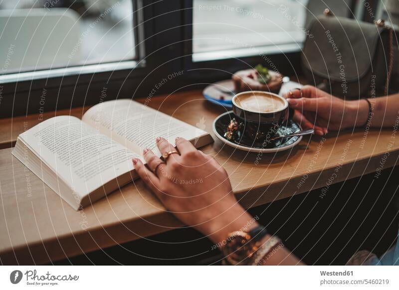 Close-up of woman with a book in a cafe human human being human beings humans person persons celibate celibates singles solitary people solitary person windows