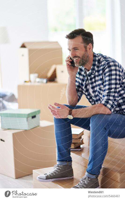 Smiling man moving into new flat talking on cell phone smiling smile on the phone call telephoning On The Telephone calling men males mobile phone mobiles