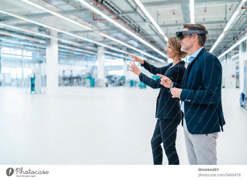 Businessman with AR glasses and businesswoman in a factory hall business life business world business person businesspeople associate associates