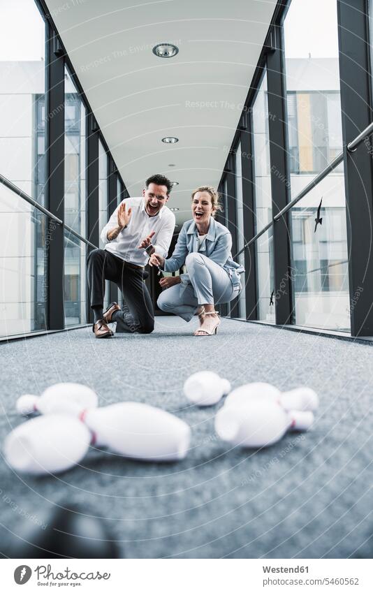 Cheering businessman and businessman in office passageway with fallen pins businesswoman businesswomen business woman business women Office Offices jubilation