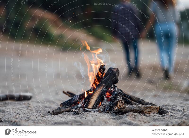 Burning campfire at the riverside, couple in background summer summer time summery summertime young couple young couples young twosome young twosomes Camp Fire