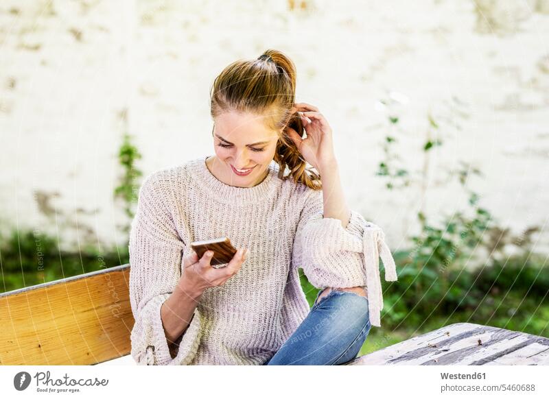 Smiling woman looking at cell phone at courtyard eyeing Smartphone iPhone Smartphones courtyards courts females women smiling smile view seeing viewing