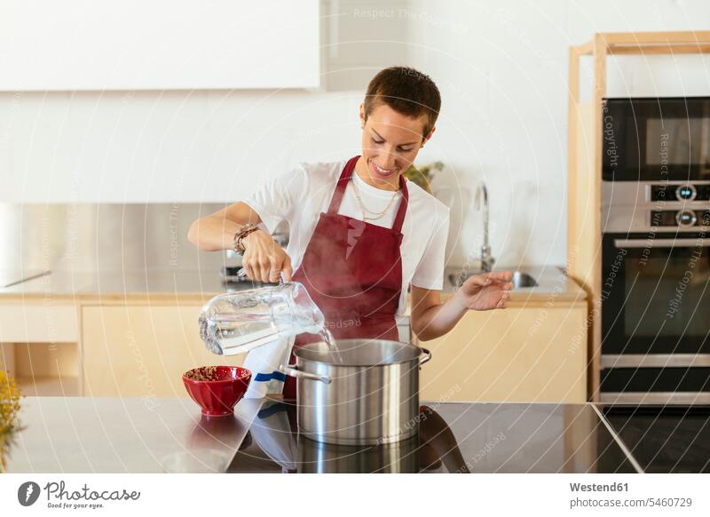 Woman boiling water in cooking pot in kitchen Cooking Pot Pots Cooking Pots woman females women female cook Adults grown-ups grownups adult people persons