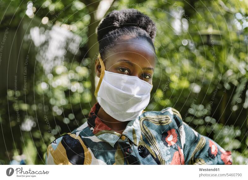 Portrait of young woman wearing white textile protective mask in garden dresses textiles cloth fabrics seasons summer time summertime summery colour colours