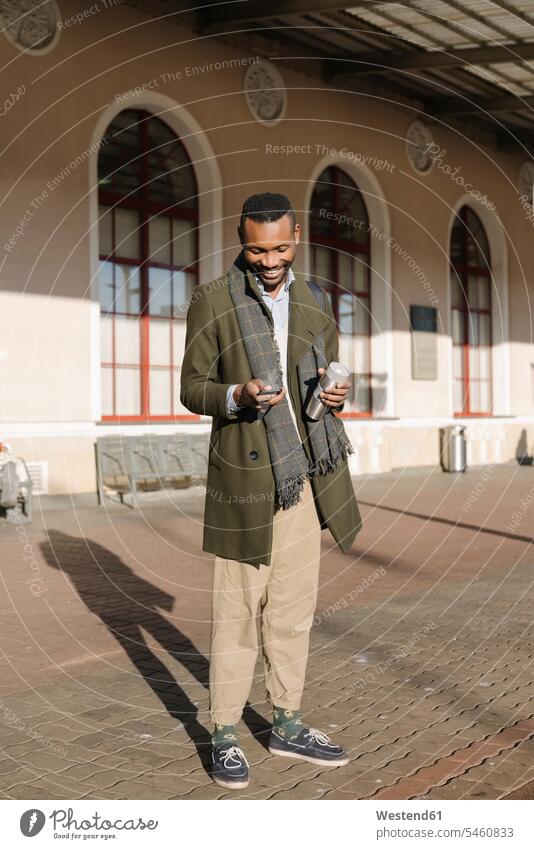 Stylish man with reusable cup using smartphone while waiting for the train business life business world business person businesspeople Business man Business men